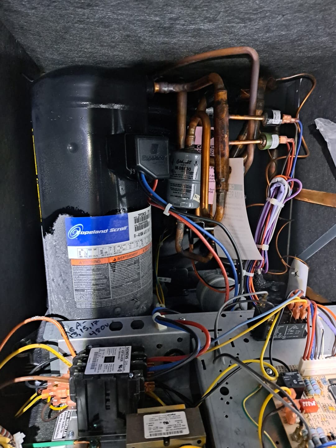Refrigeration compressor system with copper tubing and electrical connections inside unit.