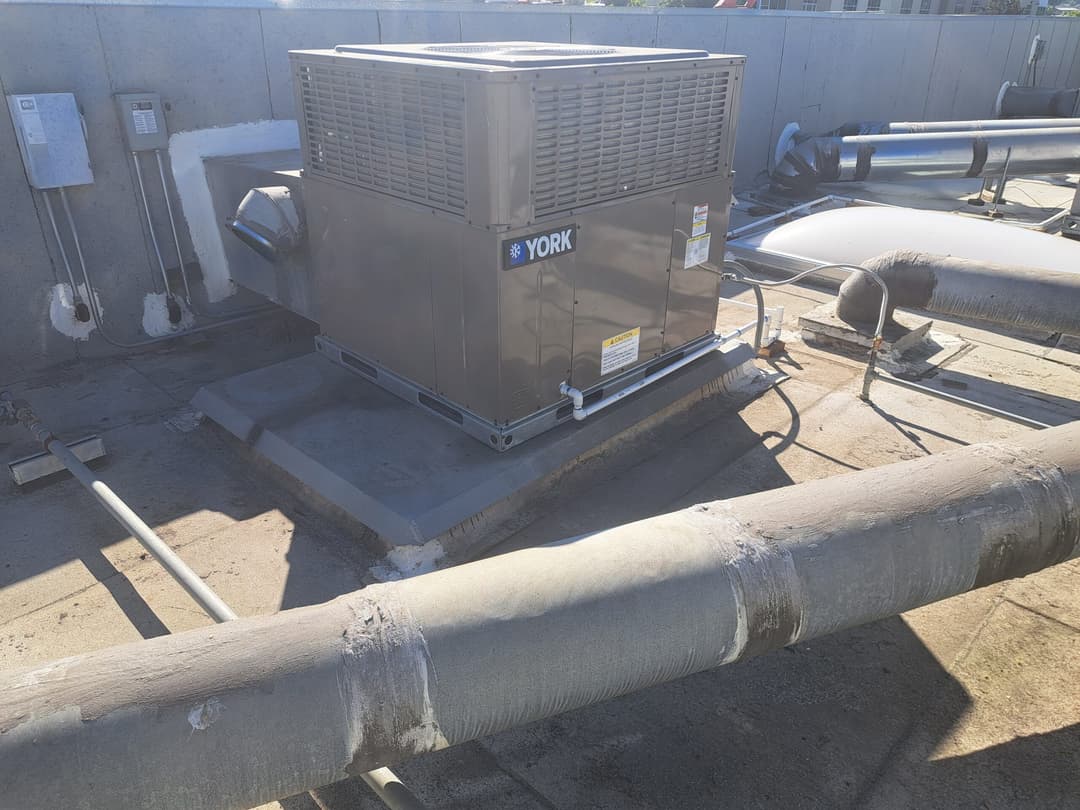 York rooftop HVAC unit on a commercial building with exposed piping and rooftop surface.