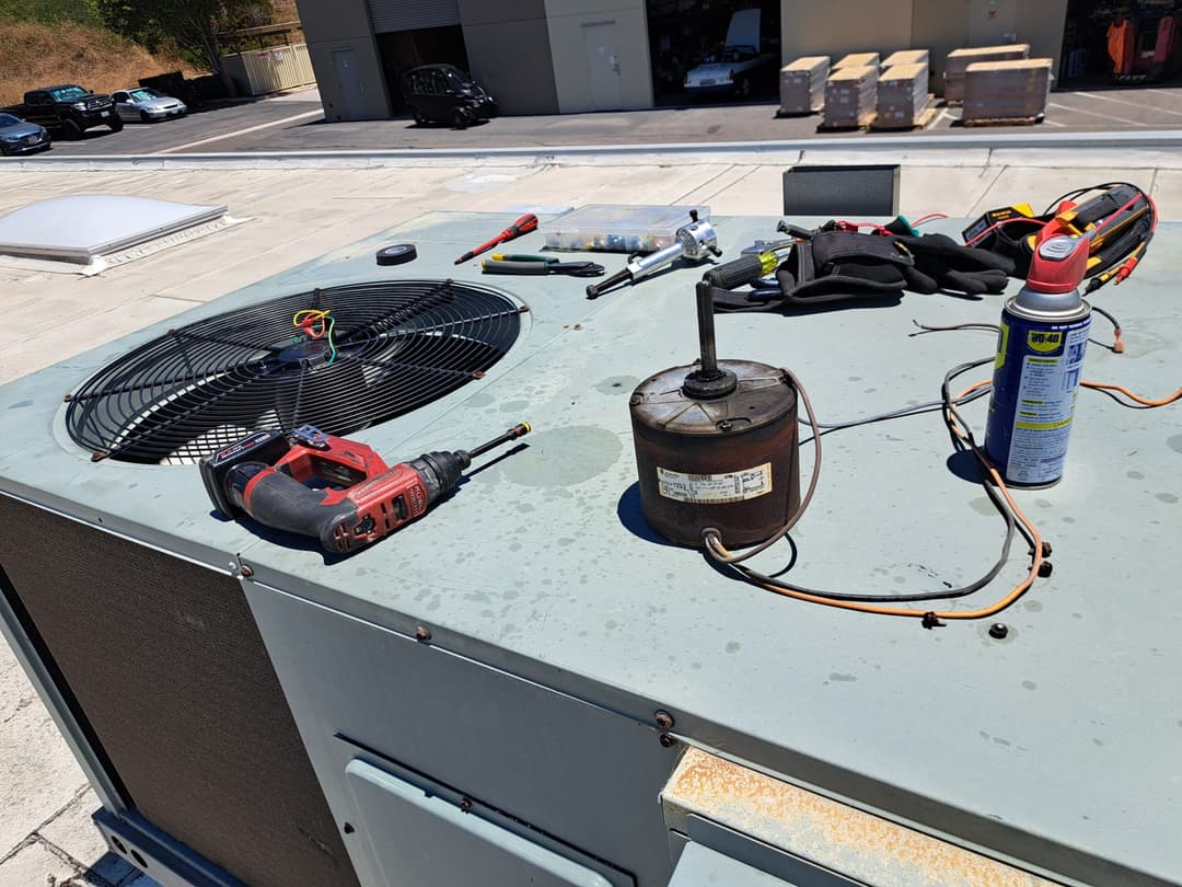 Air conditioning maintenance: tools, condenser, and components on a rooftop unit.
