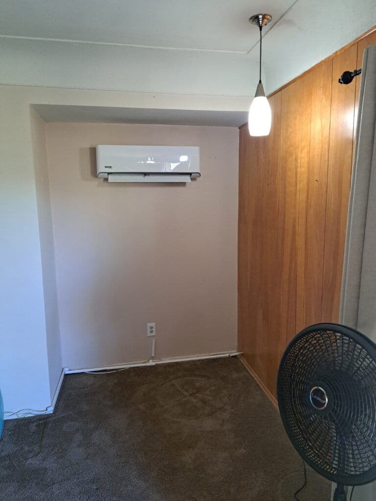 Cozy interior room featuring wall-mounted air conditioner and wooden paneling.