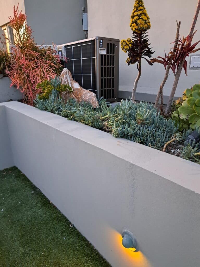 Modern landscape featuring succulents, decorative rocks, and an air conditioning unit.