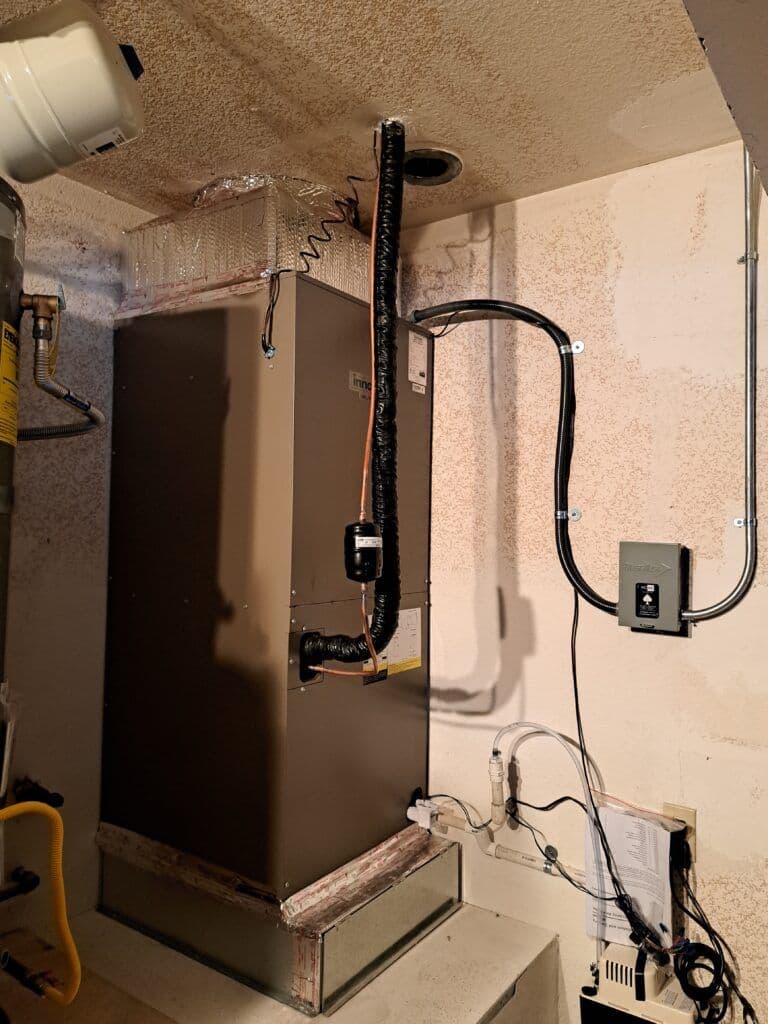 Indoor HVAC system with ducts and electrical connections in a utility room setting.