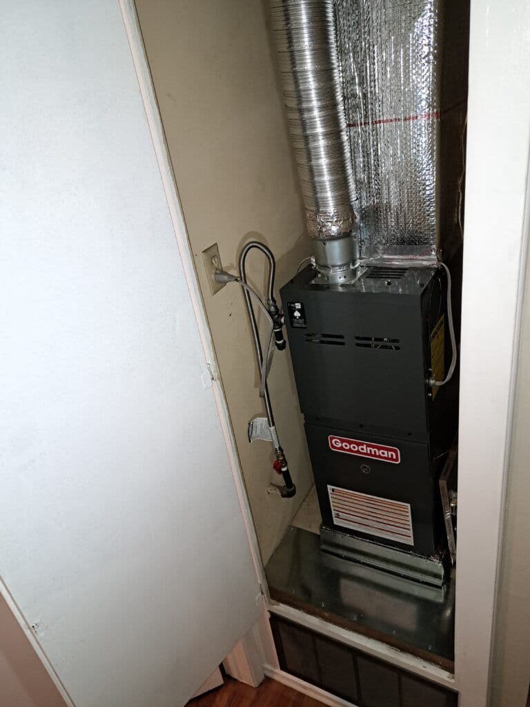 Goodman furnace installed in a small closet with ductwork visible. Heating system details.