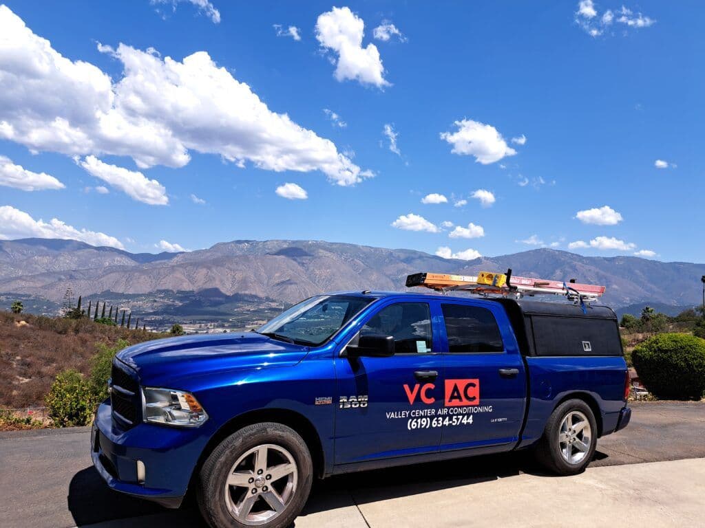 Blue truck with HVAC branding parked in scenic mountainous landscape.