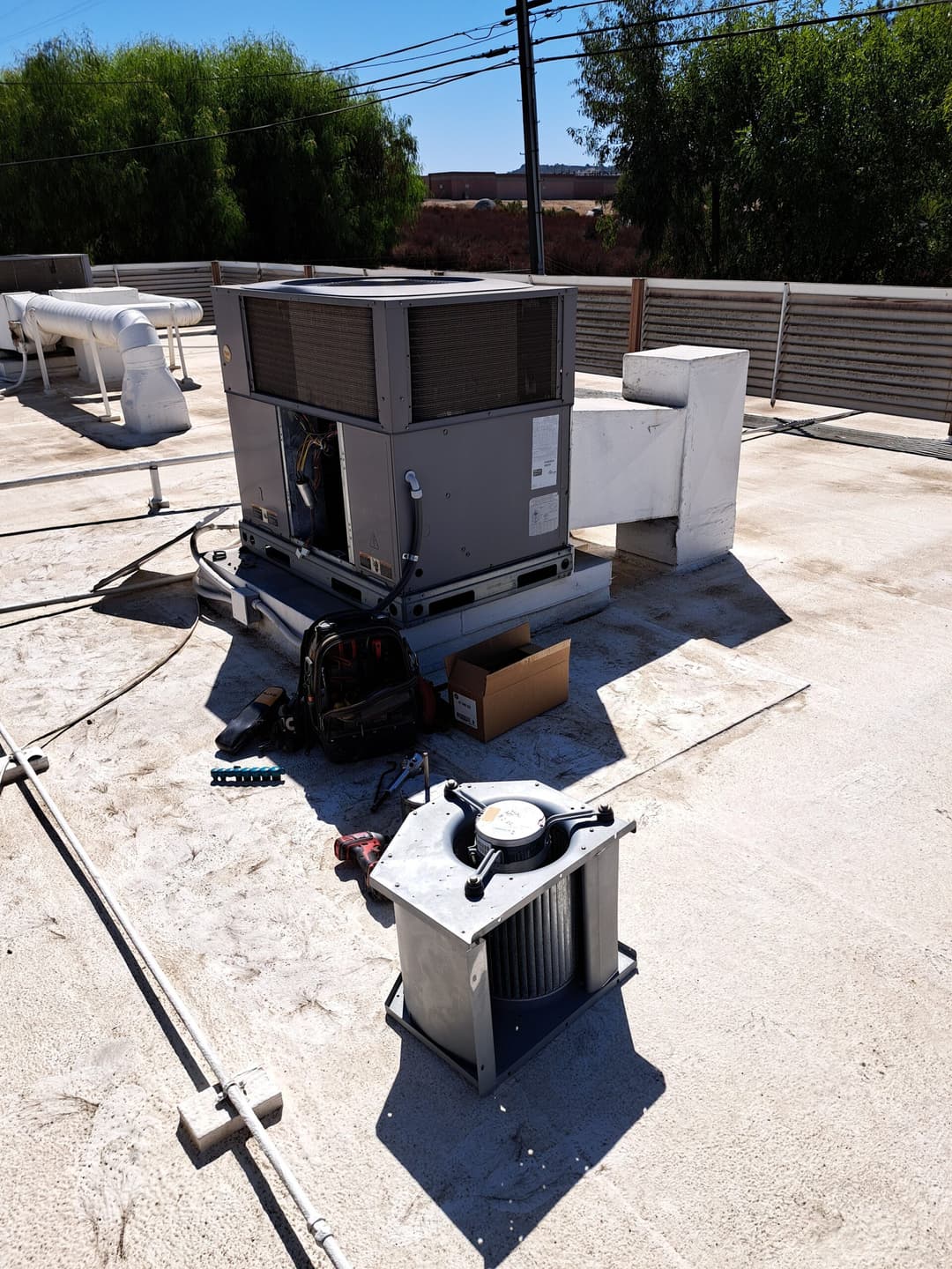 HVAC unit on a rooftop with tools and equipment nearby for maintenance.